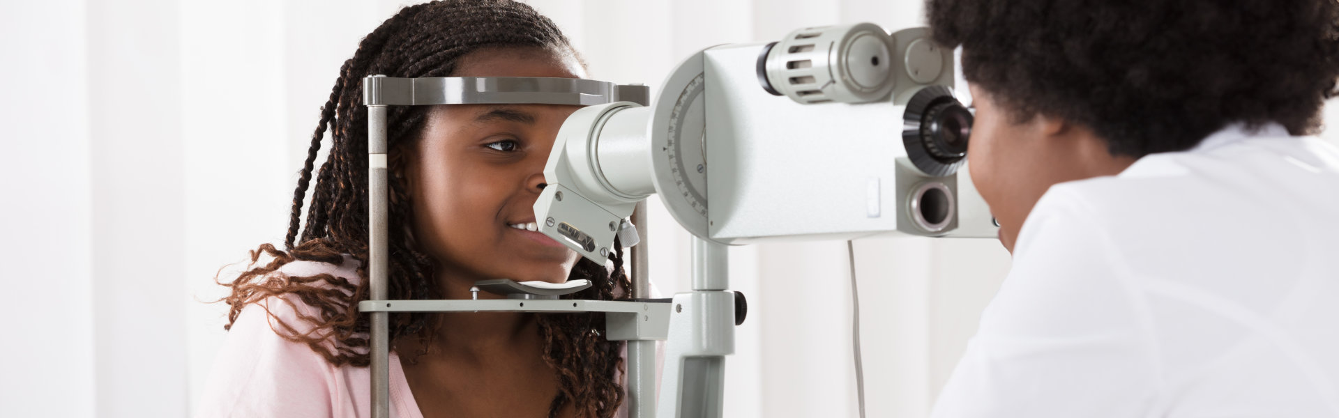 Female Optometrist Examining Patient On Phoropter In Ophthalmology Clinic